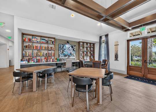 A room with a long table and chairs with a bookshelf in the background.