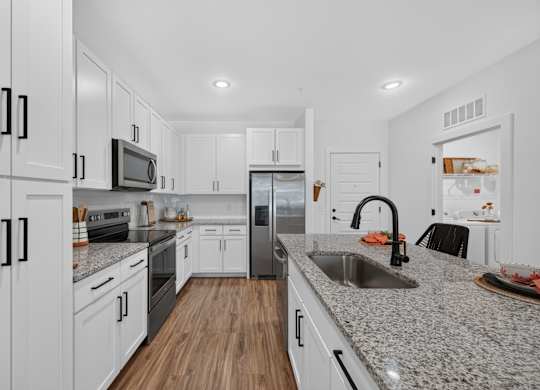 A modern kitchen with white cabinets and a granite countertop.
