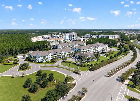 A large building complex is surrounded by a green lawn and trees.
