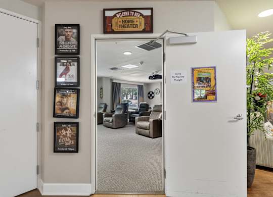 A white door is open to a room with a sign that says "Home Theater".