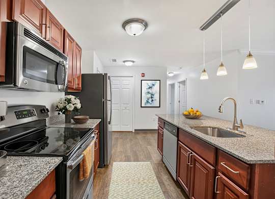 A kitchen with dark wood cabinets and granite countertops.