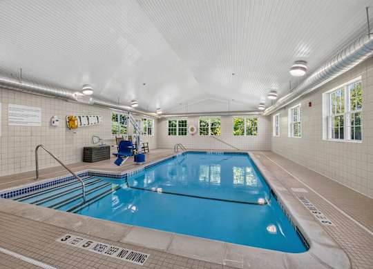 A large indoor swimming pool with a blue tiled edge and a white ceiling.