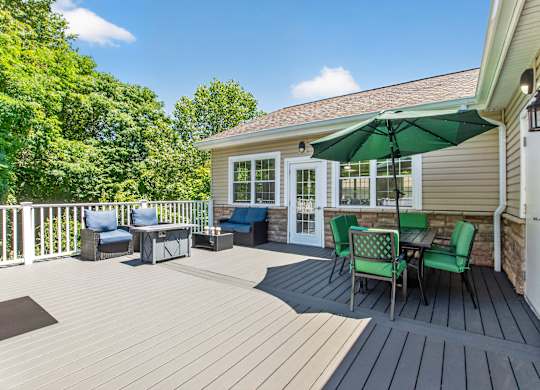 A sunny day on a wooden deck with a green umbrella.
