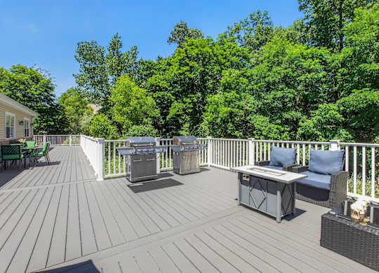 A wooden deck with a table and chairs overlooking a forest.