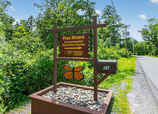 A brown sign with a butterfly on it reads