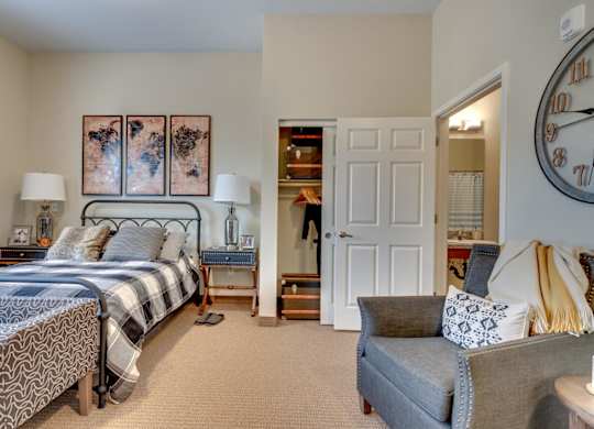 A bedroom with a bed, a couch, and a clock on the wall.
