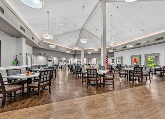 A restaurant with wooden tables and chairs and a white ceiling.