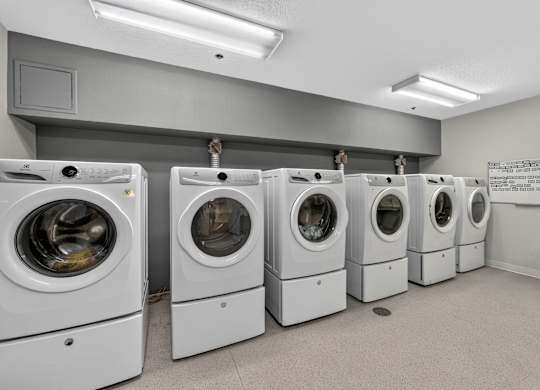 A row of white front load washing machines in a laundromat.