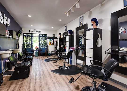 A hair salon with a wooden floor and chairs.