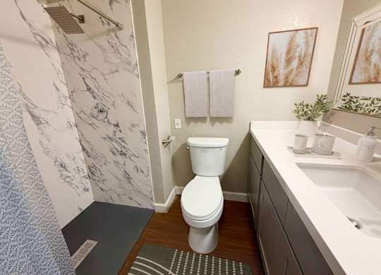 A bathroom with a toilet, sink, and shower.