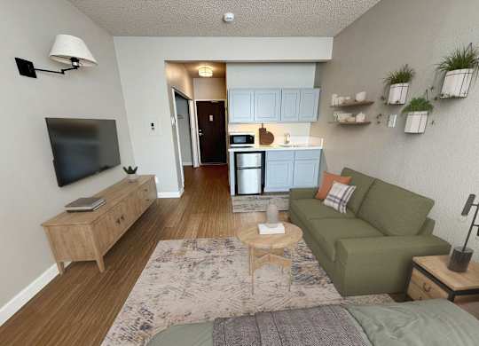 A living room with a couch, a television, and a kitchen area in the background.