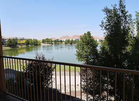 A view of a lake from a balcony with a car parked on the left.