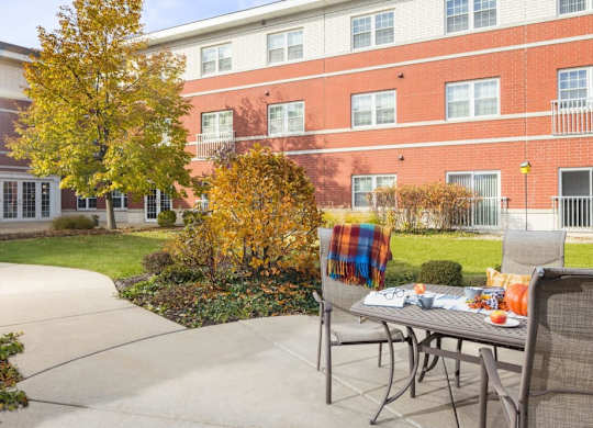 A table with a plaid blanket on it is in front of a brick building.
