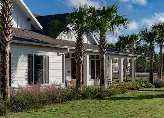 A white house with a black roof and a palm tree in front. at Atwater at Nocatee Apartments, Toledo, FL, 32081