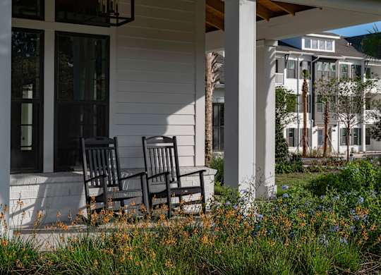 Two chairs are on the porch of a white house. at Atwater at Nocatee Apartments, Toledo, 32081