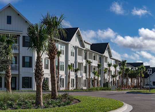 A white building with a black roof and palm trees in front. at Atwater at Nocatee Apartments, Toledo, FL