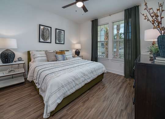 A bedroom with a bed, nightstand, and a ceiling fan. at Atwater at Nocatee Apartments, Florida