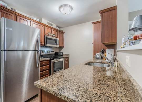 Kitchen with granite counters and stainless steel appliances at Schuyler Commons Apartments, New York