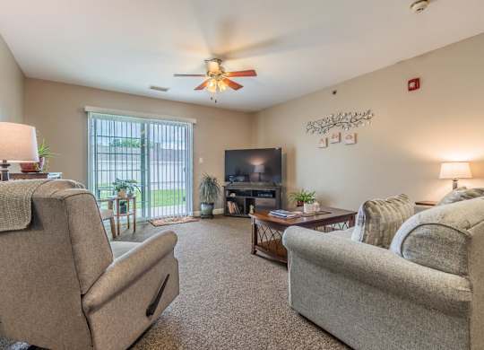 Living room with neutral furniture and ceiling fan at Schuyler Commons Apartments, New York, 13502