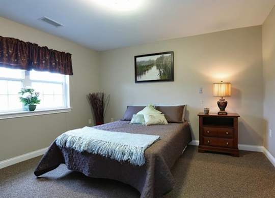 Cozy bedroom with decorative throw pillows at Schuyler Commons Apartments, Utica, 13502