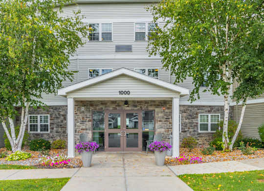 Three story apartment building entrance with stone accents at Schuyler Commons Apartments, New York