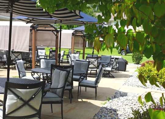 Outdoor terrace with covered seating and umbrellas at Schuyler Commons Apartments, Utica