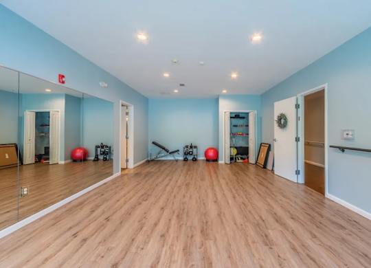 Fitness studio with exercise equipment and mirrors at Glenmont Abbey Village, 55+ Apartments, Glenmont, New Jersey