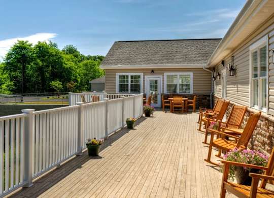 Spacious deck with wooden furniture and white railings at Glenmont Abbey Village, 55+ Apartments, Glenmont, NJ