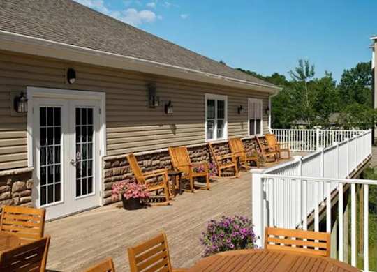 Covered deck with rocking chairs and white railing at Glenmont Abbey Village, 55+ Apartments, Glenmont, 12077