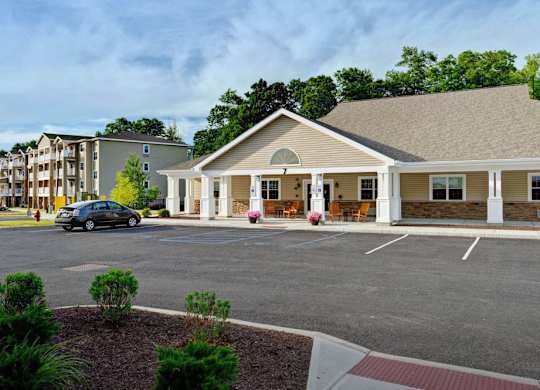 Clubhouse entrance with covered porch and parking at Glenmont Abbey Village, 55+ Apartments, Glenmont
