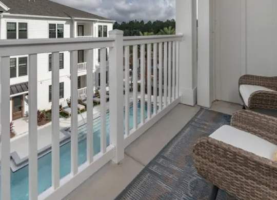 A white balcony with a pool and chairs. at Atwater at Nocatee Apartments, Toledo, FL, 32081