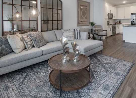 A modern living room with a grey sofa and a wooden coffee table. at Atwater at Nocatee Apartments, Toledo, Florida