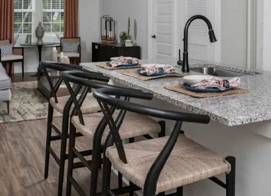 A kitchen with a table and chairs in the foreground and a window with curtains in the background. at Atwater at Nocatee Apartments, Toledo, Florida