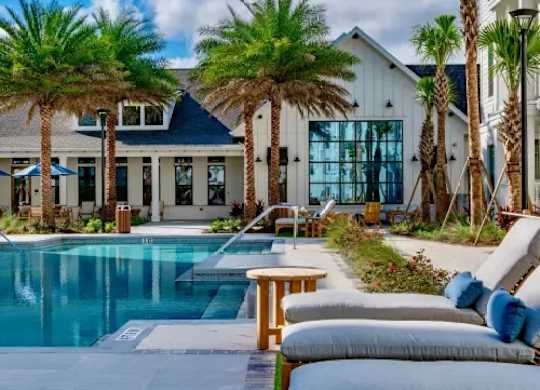 A poolside area with lounge chairs and a table. at Atwater at Nocatee Apartments, Florida, 32081