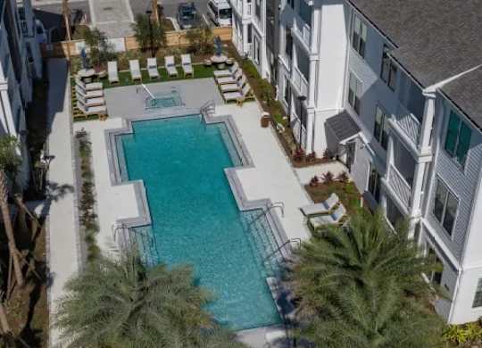 A swimming pool surrounded by palm trees and white buildings. at Atwater at Nocatee Apartments, Toledo, FL