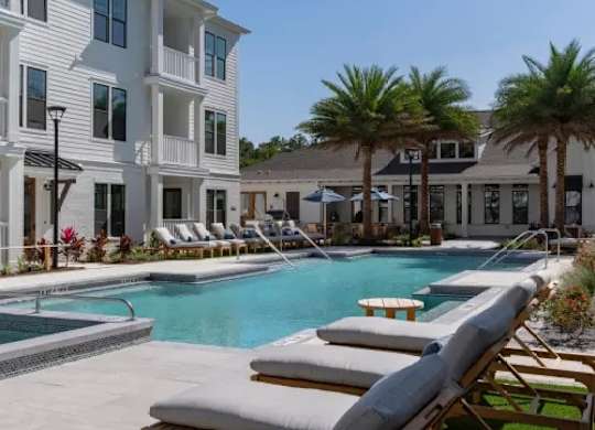 A pool with lounge chairs and a building in the background. at Atwater at Nocatee Apartments, Toledo, 32081