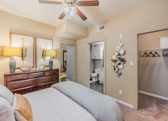 A bedroom with a bed, dresser, and ceiling fan. at The Spring at Silverton Apartments, Fort Worth, 76133