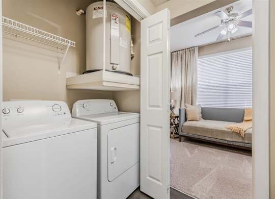 A white washing machine and dryer in a small laundry room. at The Spring at Silverton Apartments, Fort Worth, TX, 76133