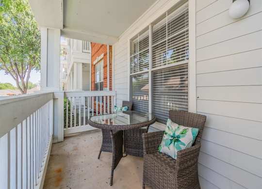 A patio with a table, chairs and a white railing. at The Spring at Silverton Apartments, Fort Worth