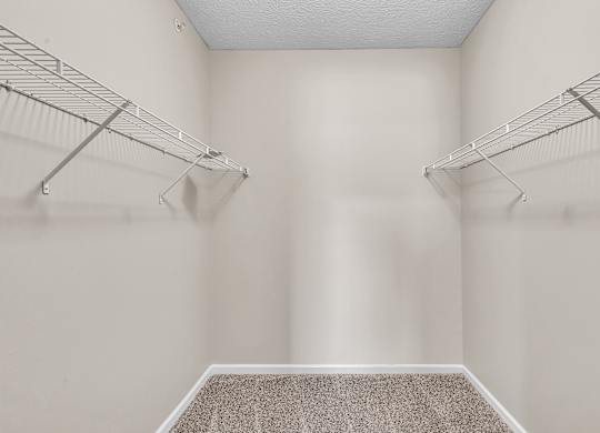 A walk-in closet with a carpeted floor and metal racks.