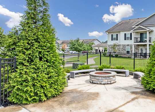 A white house with a black fence and a fire pit in the middle of the yard.