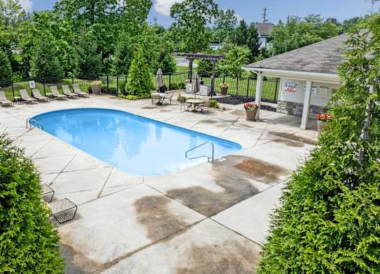 A large outdoor swimming pool surrounded by trees and a pavilion.