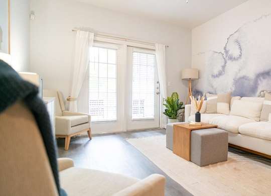 A living room with a white sofa, a wooden side table, and a large painting on the wall.