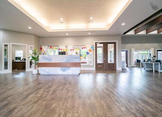 A spacious room with wooden floors and a white reception desk.