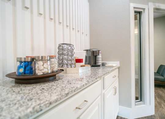 A kitchen counter with a jar of blue candies and a silver container.