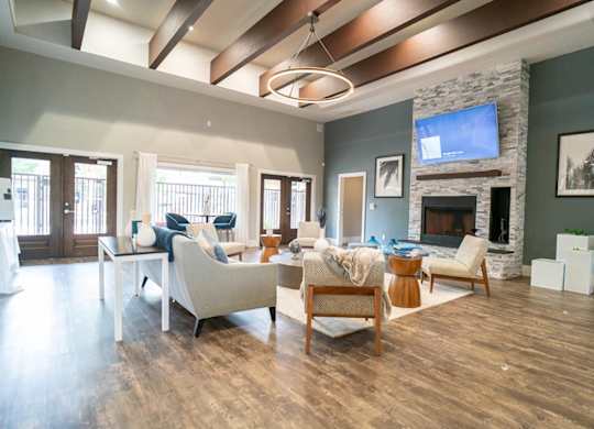 A living room with a stone fireplace and a television mounted above it.