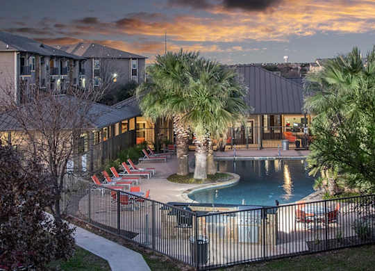 A pool surrounded by palm trees and chairs.