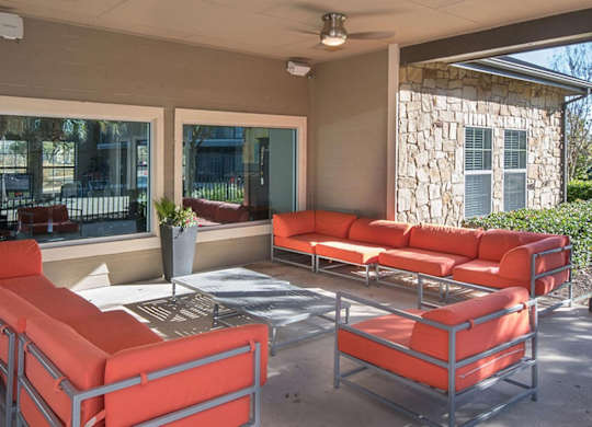 A patio with orange furniture and a stone wall.