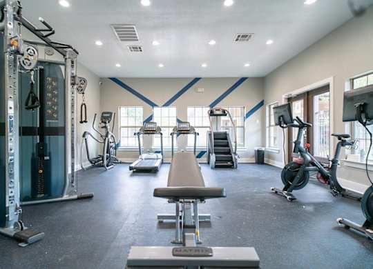 A gym with a variety of equipment including treadmills, exercise bikes, and weight machines.
