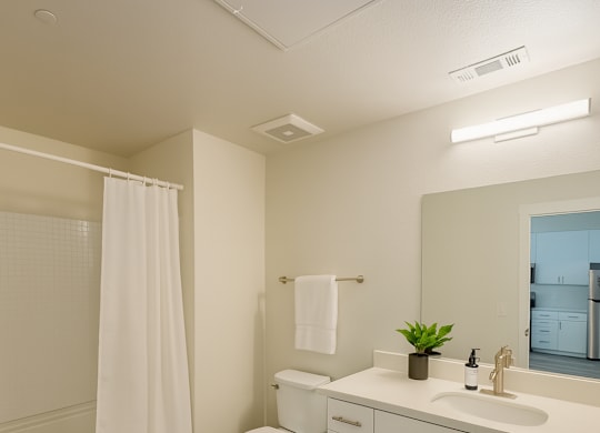 A white bathroom with a toilet, sink, and shower.